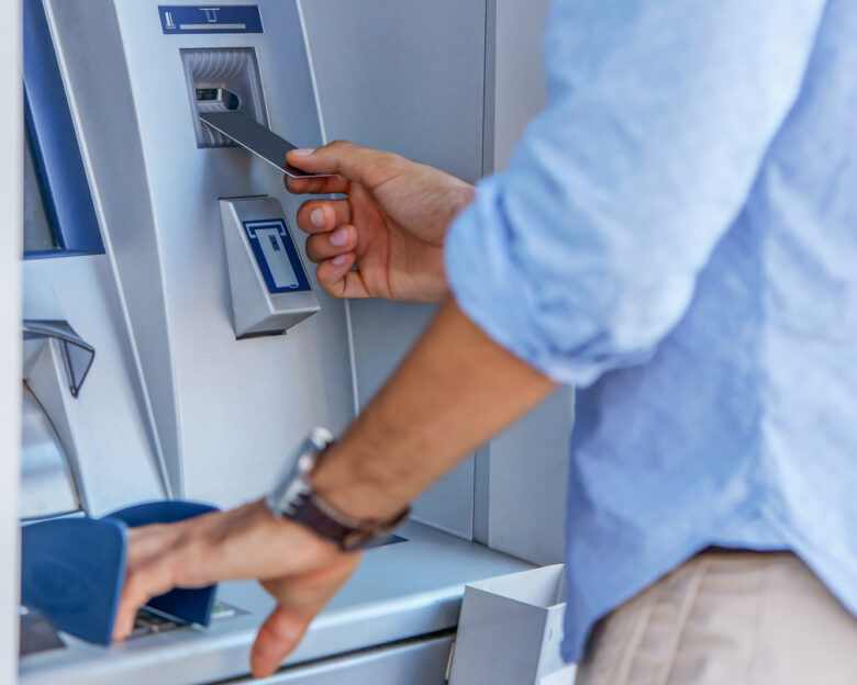 Man using a street ATM machine and withdrawing money, close up photo