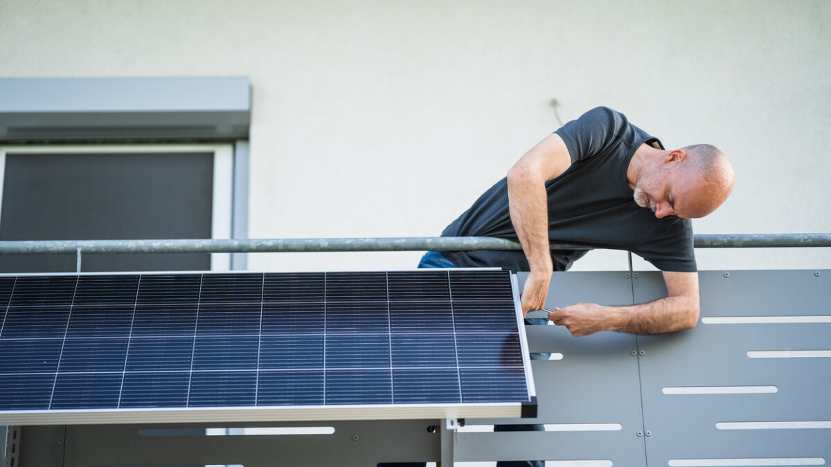 man installing adjustable solar panel on balcony of his house