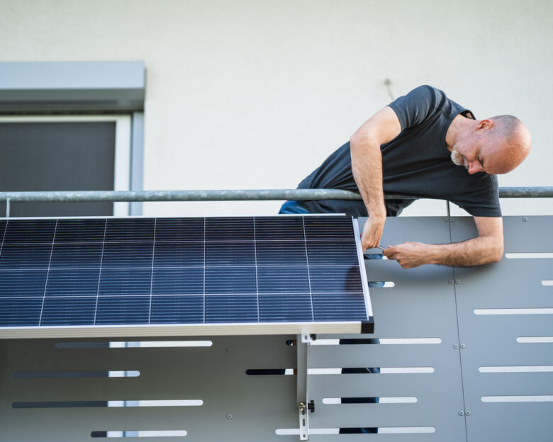 man installing adjustable solar panel on balcony of his house