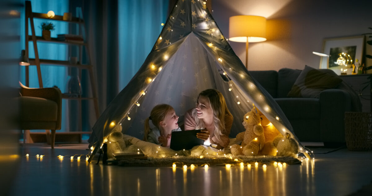 Night, home and mother with girl, tablet and bonding together with love, internet and social media. Family, mama and kid with technology, happiness and relax in a living room, tent and online movie