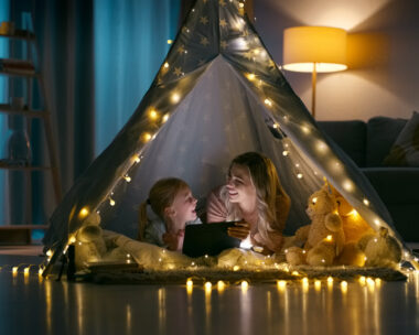 Night, home and mother with girl, tablet and bonding together with love, internet and social media. Family, mama and kid with technology, happiness and relax in a living room, tent and online movie