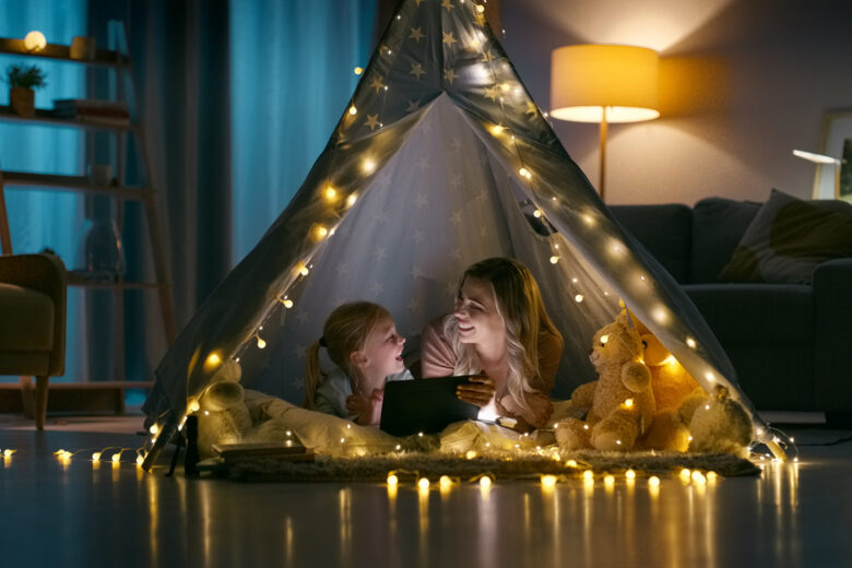 Night, home and mother with girl, tablet and bonding together with love, internet and social media. Family, mama and kid with technology, happiness and relax in a living room, tent and online movie