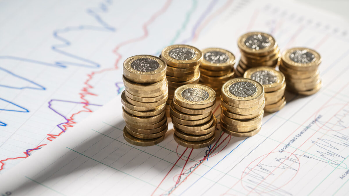 Stack of pound coins on financial graphs and figures balance sheet