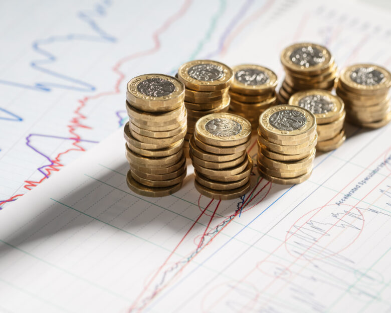Stack of pound coins on financial graphs and figures balance sheet