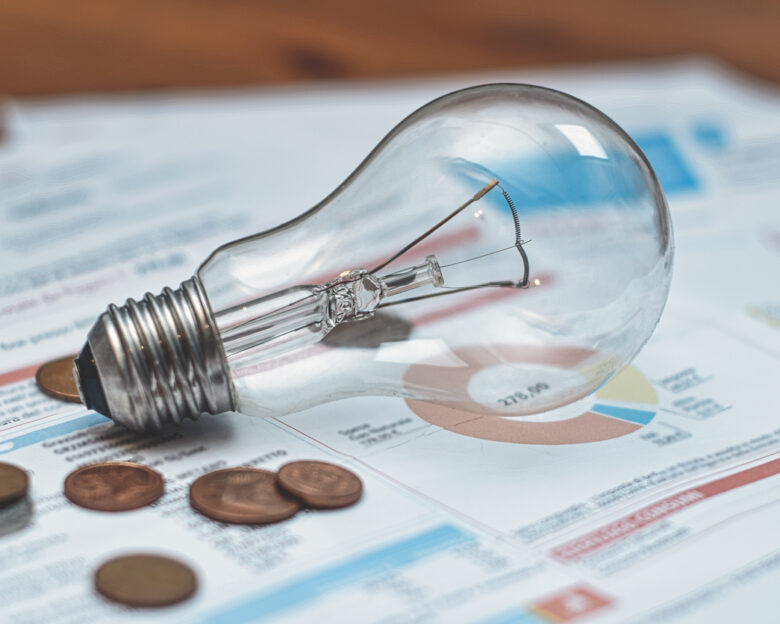 Detail of electricity bills with light bulb and coins