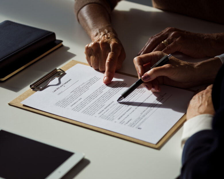 Female lawyer explaining the will to senior woman. Close up of hands, unrecognizable people.