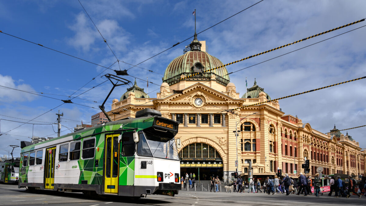 Melbourne, Victoria, Australia - March 28, 2023: A modern tram and pedestrians crossing the intersection in front of Flinders Street Station in Melbourne.