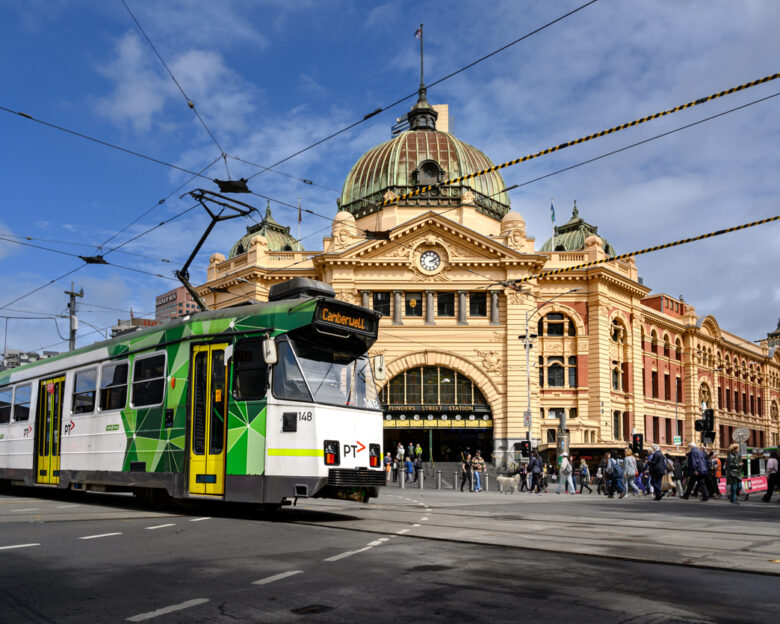 Melbourne, Victoria, Australia - March 28, 2023: A modern tram and pedestrians crossing the intersection in front of Flinders Street Station in Melbourne.