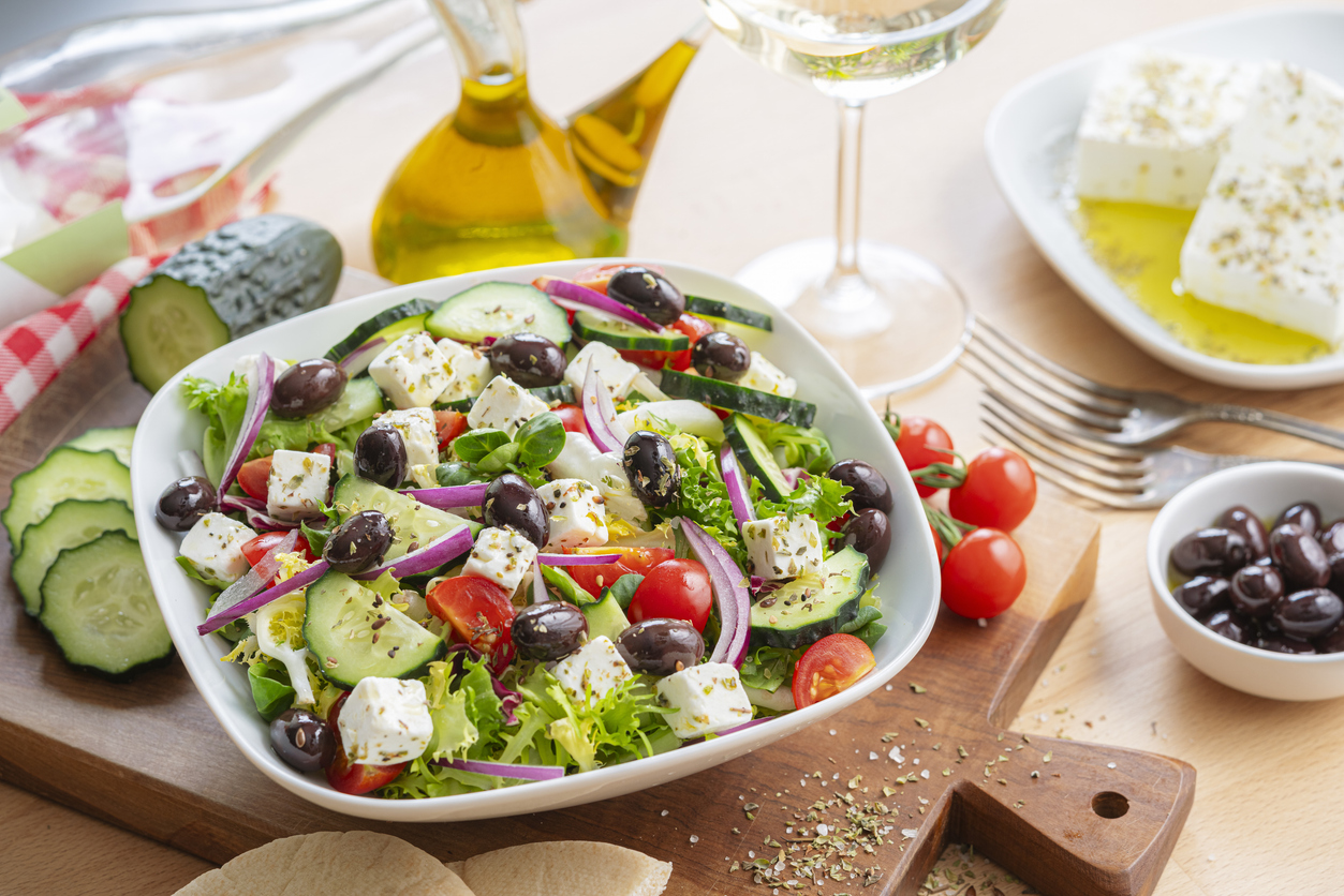Healthy and fresh Greek salad plate bowl on dining table. Feta cheese, black olives, tomatoes and cucumber