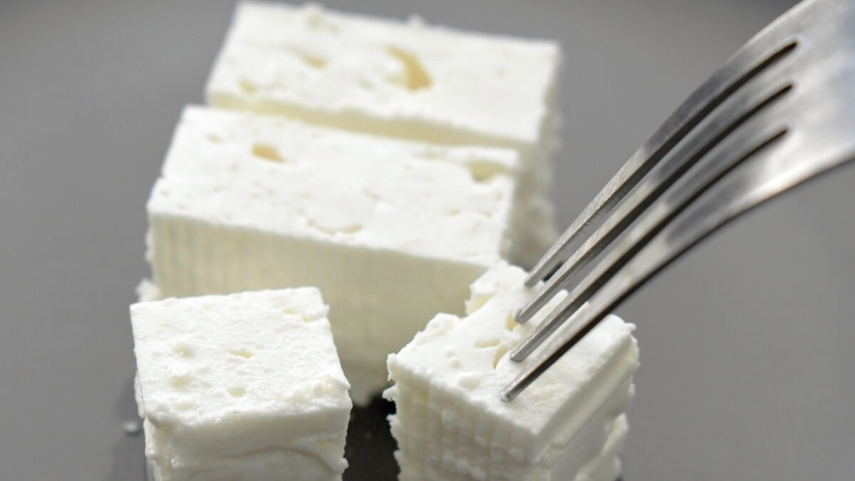 Feta cheese with fork on a plate. Traditional Greek food.