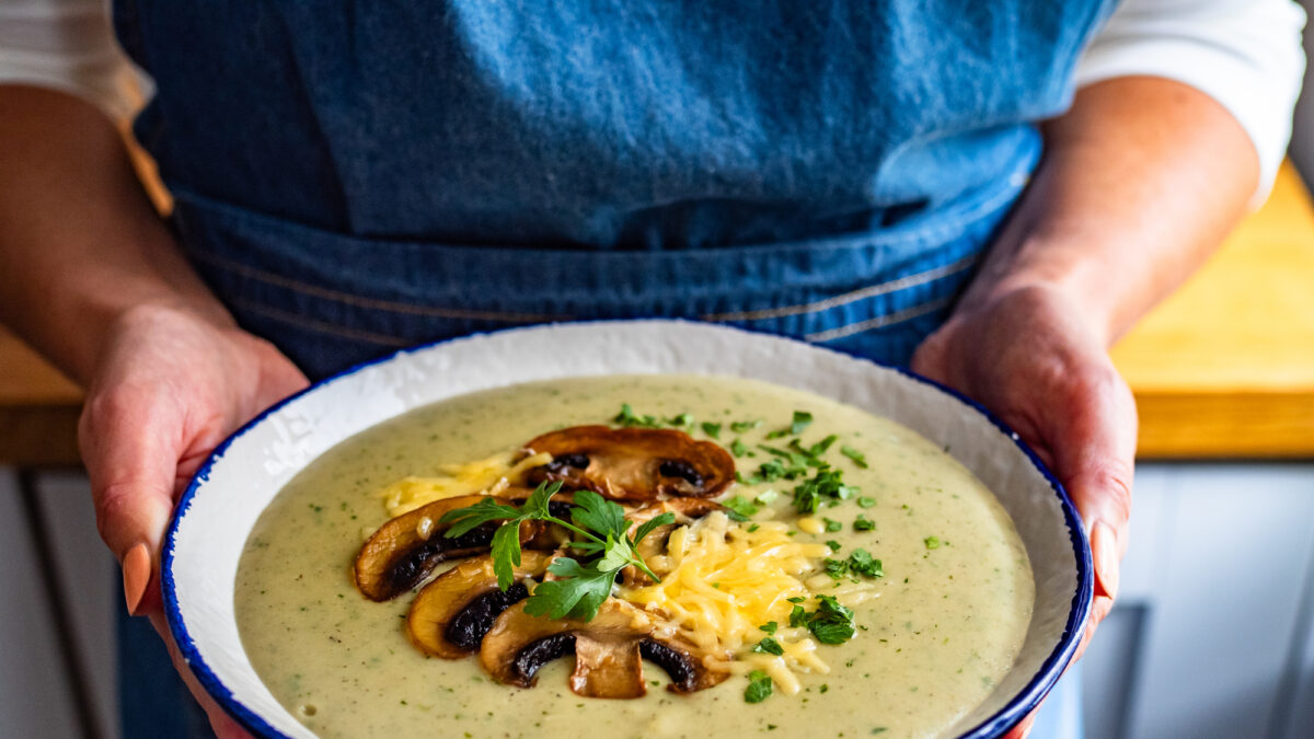 Woman holding bowl with creamy mushroom soup, close-up