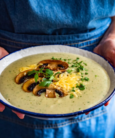Woman holding bowl with creamy mushroom soup, close-up