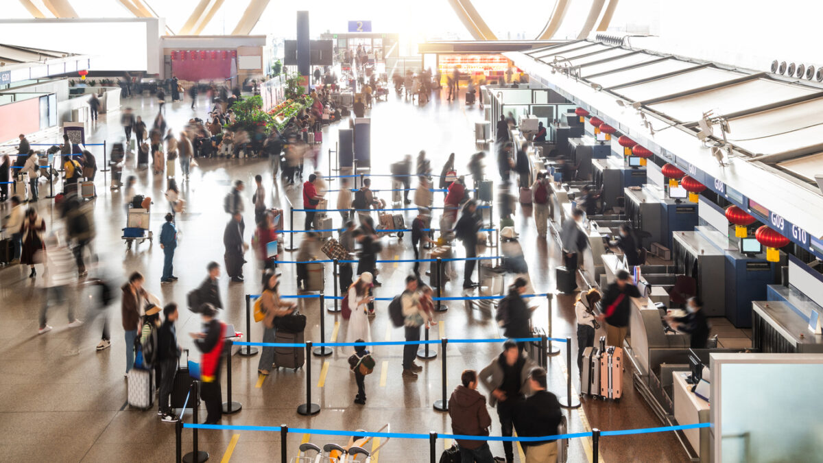 Crowded commuter people with luggage in airport waiting for check-in