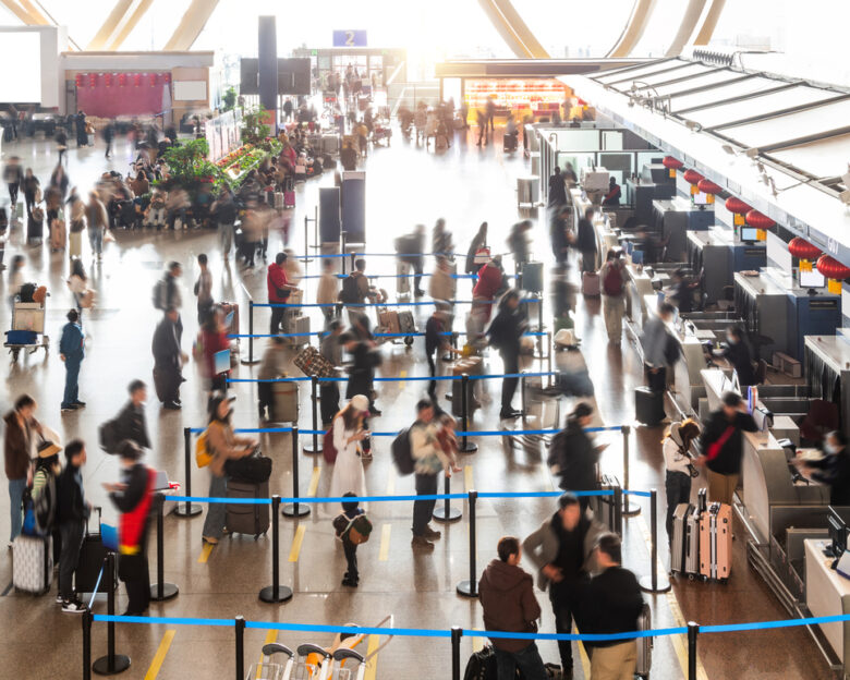 Crowded commuter people with luggage in airport waiting for check-in