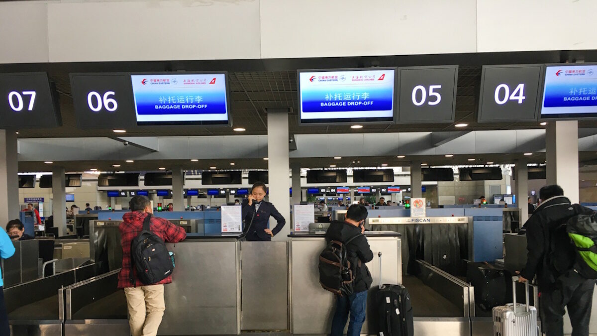 Shanghai, China - December 4, 2017: Passengers are approaching check-in counters in Shanghai Pudong international airport terminal. Pudong international airport is a major aviation hub of China.