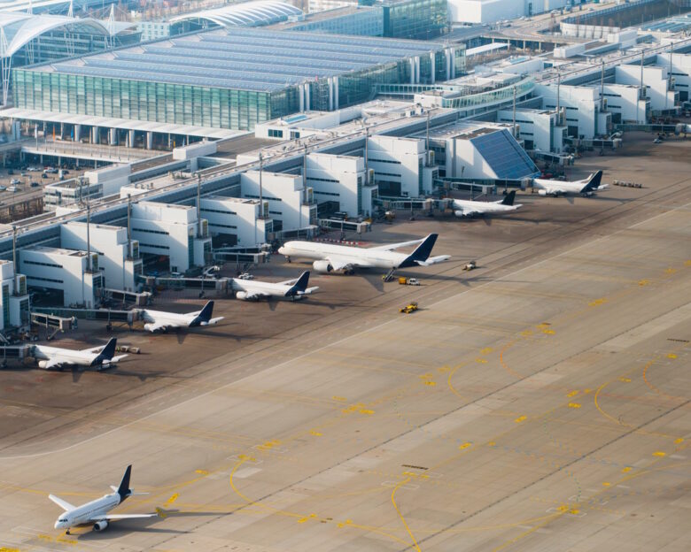 Multiple aircraft docked at terminal gates seen from above. Airport operations and boarding. Munich International Airport, Germany.