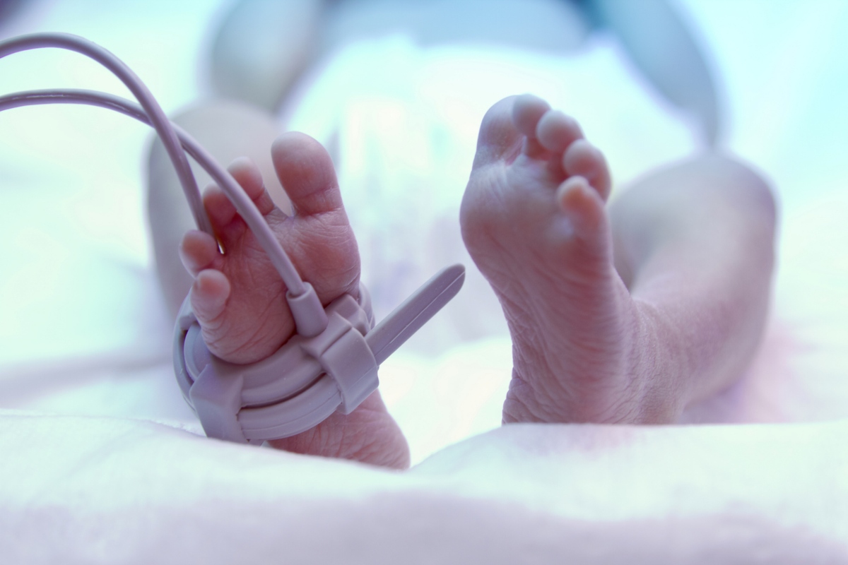 Feet of new born baby under ultraviolet lamp in the incubator