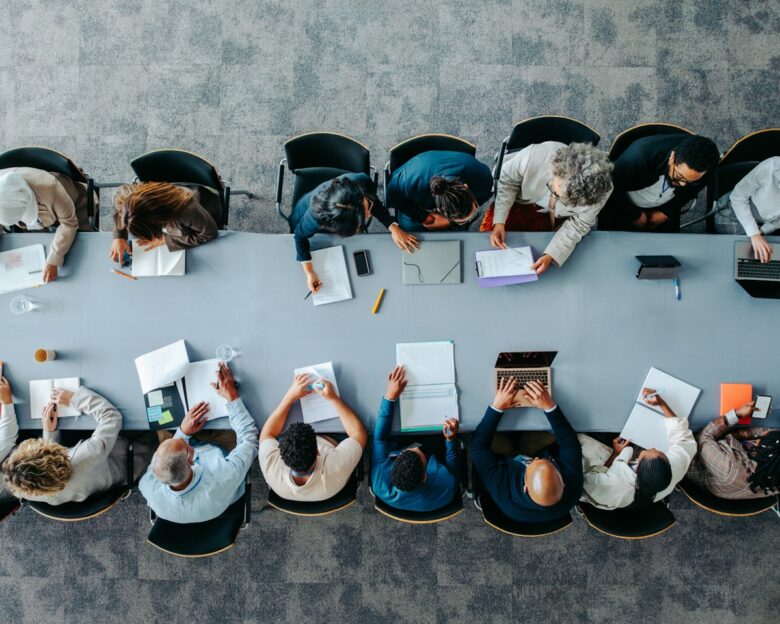 Top view of diverse business group in office meeting, collaborating and discussing around a large table.