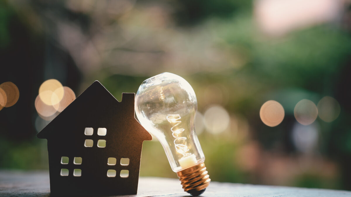Light bulb with wood house on the table, a symbol for construction, Creative light bulb idea, power energy or business idea concept ecology, loan, mortgage, property or home