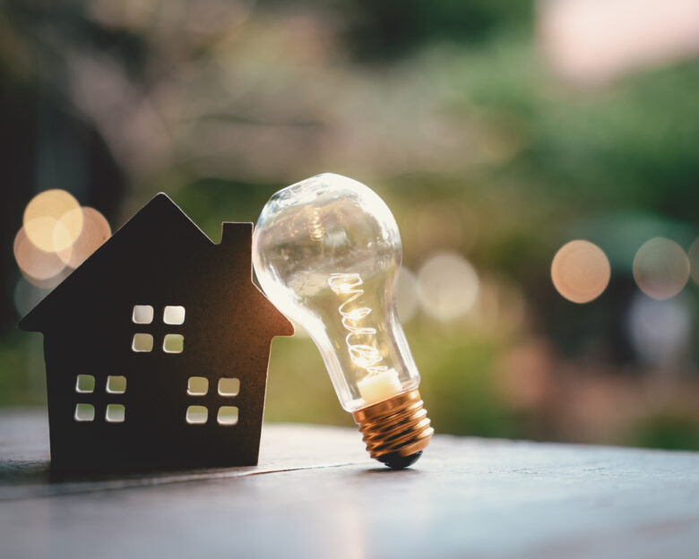 Light bulb with wood house on the table, a symbol for construction, Creative light bulb idea, power energy or business idea concept ecology, loan, mortgage, property or home