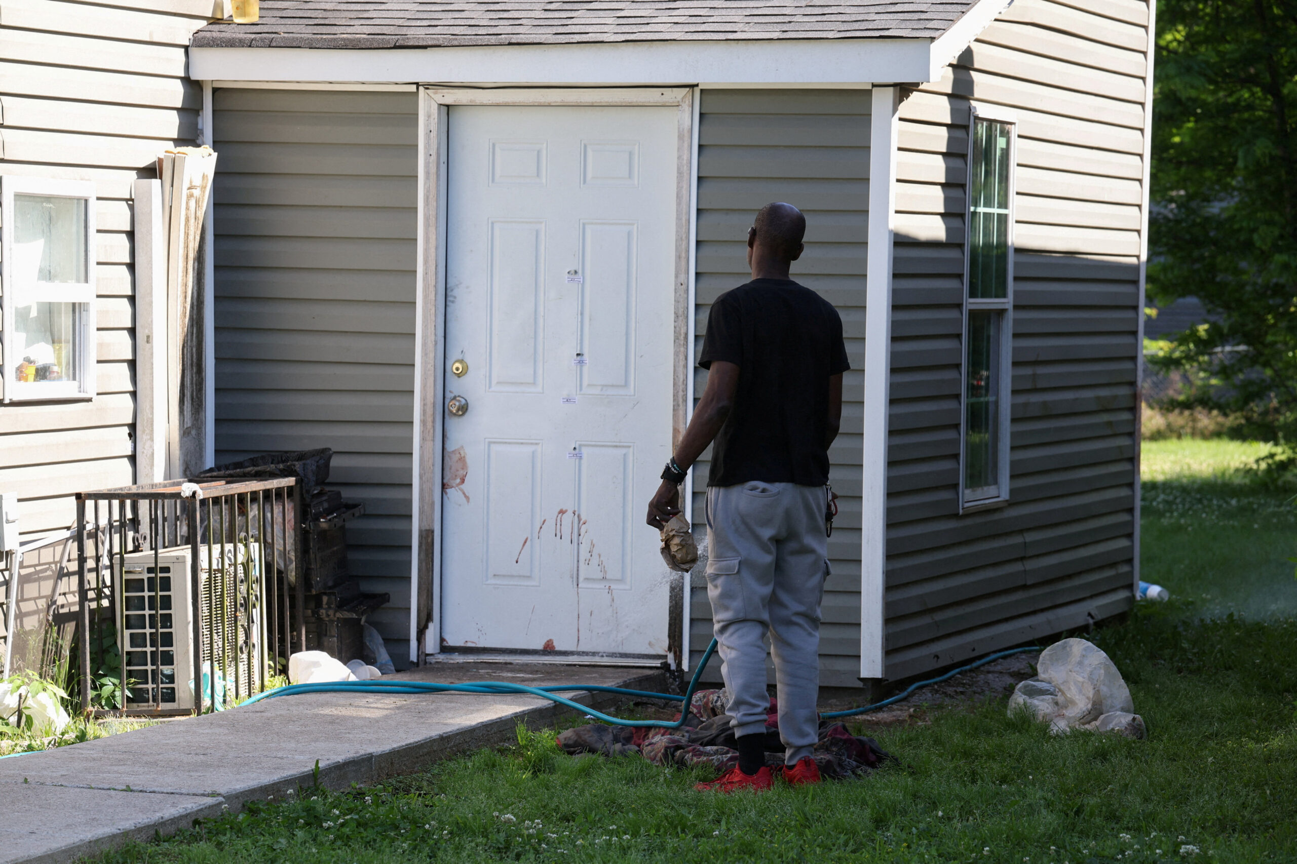 SENSITIVE MATERIAL. THIS IMAGE MAY OFFEND OR DISTURB A man uses a water hose to wash blood from a door after children, with ages ranging from 1 to 14, were killed in a mass shooting incident described as domestic violence, in Shreveport, Louisiana, U.S. April 19, 2026. REUTERS/Kevin Bartram TPX IMAGES OF THE DAY
