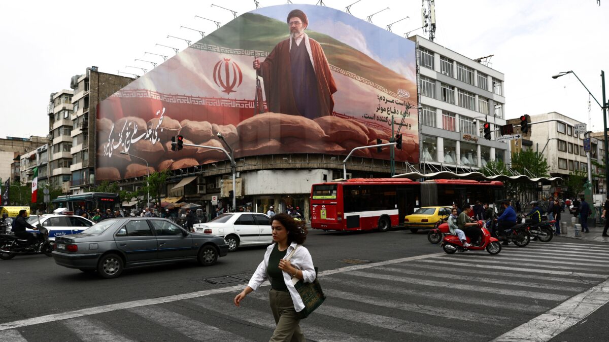 Γυναίκα περπατάει μπροστά από μία τεράστια πινακίδα του νέου ηγέτη του Ιράν Μοτζτάμπα Χαμενεΐ