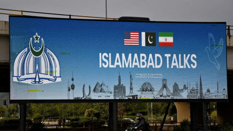 FILE PHOTO: A man rides his motorbike past a billboard installed alongside a road as Pakistan prepares to host the U.S. and Iran for peace talks, in Islamabad, Pakistan, April 10, 2026. REUTERS/Waseem Khan/File Photo