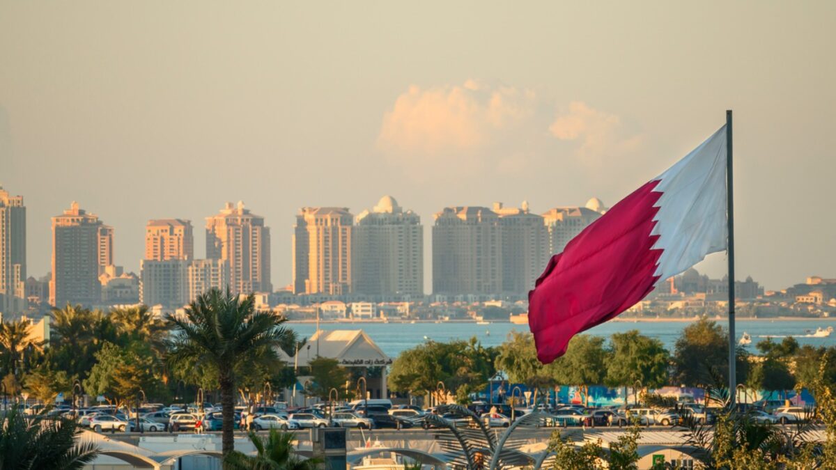Doha, Qatar - December 20, 2024: Waving Qatar flag in Doha city center with city center in background