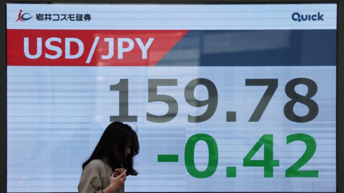 A woman walks past a screen displaying the exchange rate between Japanese yen and U.S. dollar outside a brokerage in Tokyo, Japan, March 30, 2026. REUTERS/Issei Kato