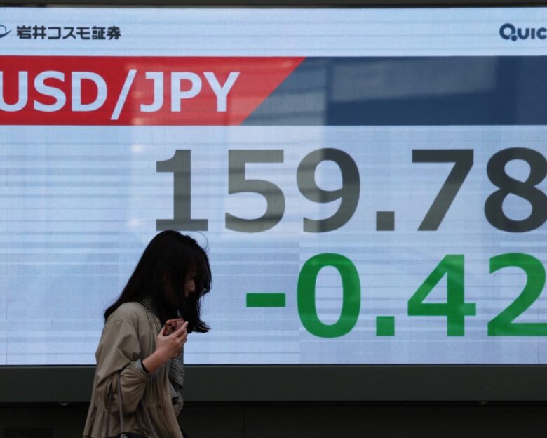 A woman walks past a screen displaying the exchange rate between Japanese yen and U.S. dollar outside a brokerage in Tokyo, Japan, March 30, 2026. REUTERS/Issei Kato