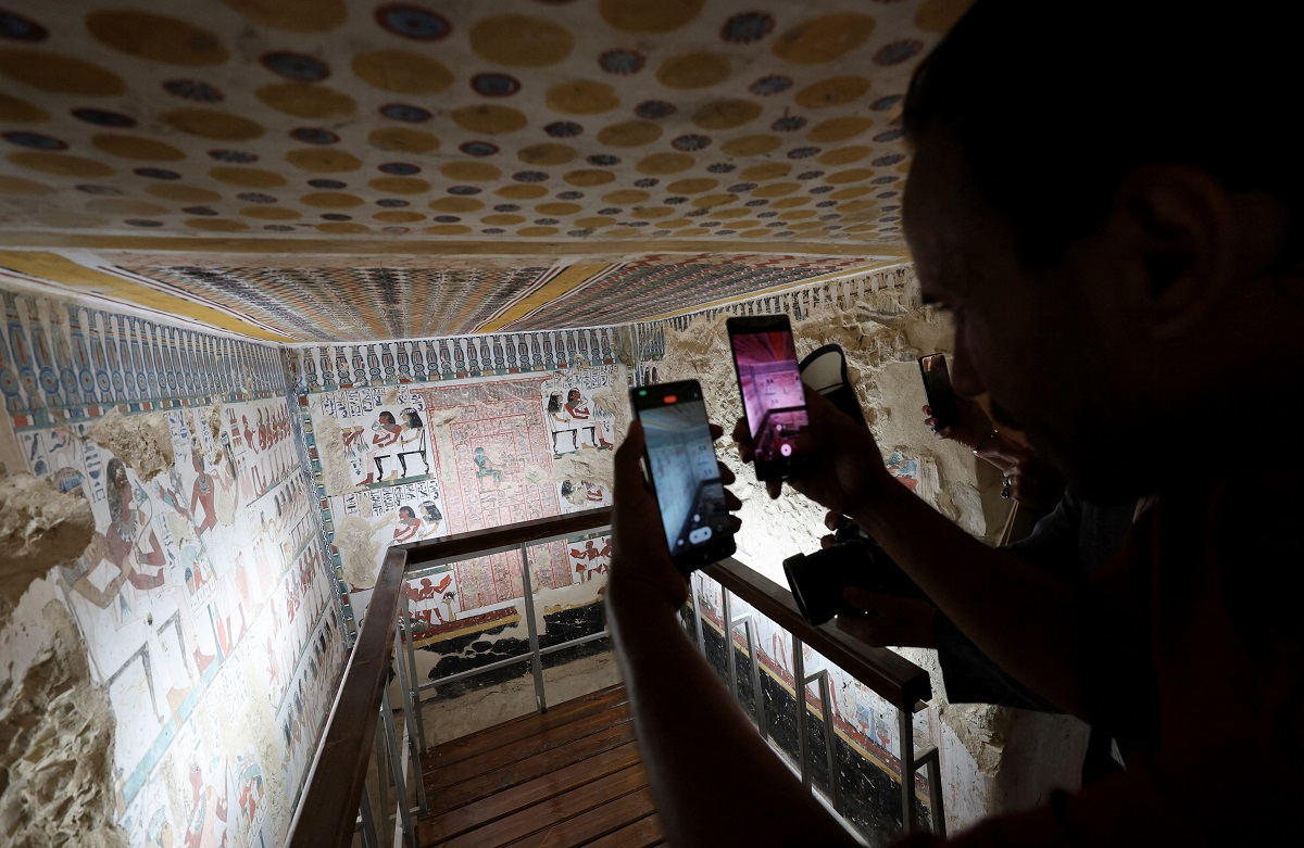 A visitor takes a photo inside the recently restored ancient "Samut" (TT417) in the El-Khokha necropolis on the west bank of the Nile in Luxor, where Egyptian authorities have announced the completion of restoration work on two 18th Dynasty tombs belonging to Amenhotep Rabuia and his son Samut, dating back to the reigns of Pharaohs Thutmose III and Thutmose IV, that contain scenes illustrating daily life, funerary practices, and religious imagery from ancient Egypt, in Egypt, May 14, 2026. REUTERS