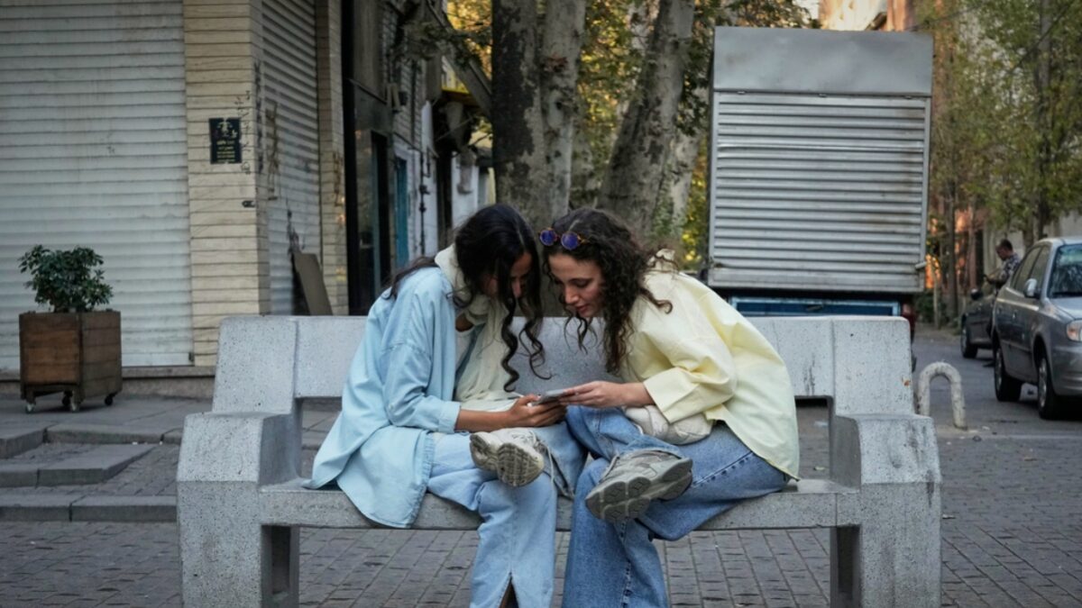 FILE - Two women use a smartphone in northern Tehran, Iran, Sept. 28, 2025.