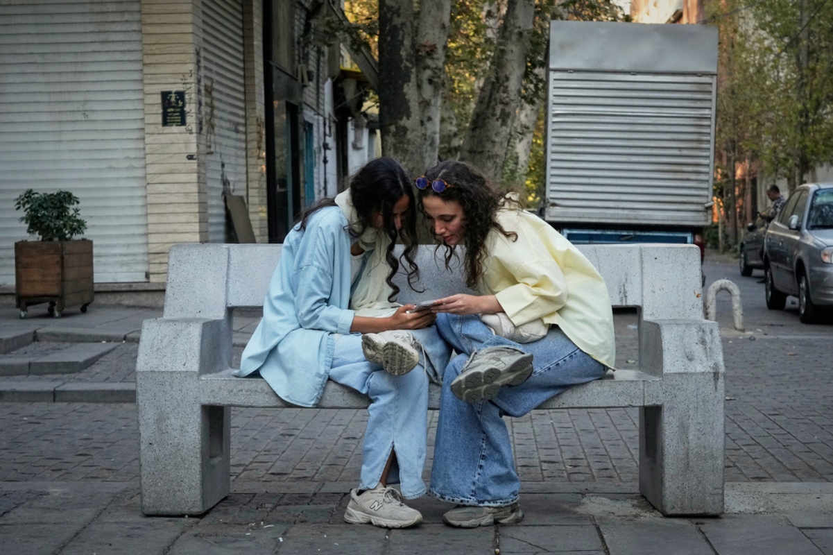 FILE - Two women use a smartphone in northern Tehran, Iran, Sept. 28, 2025.