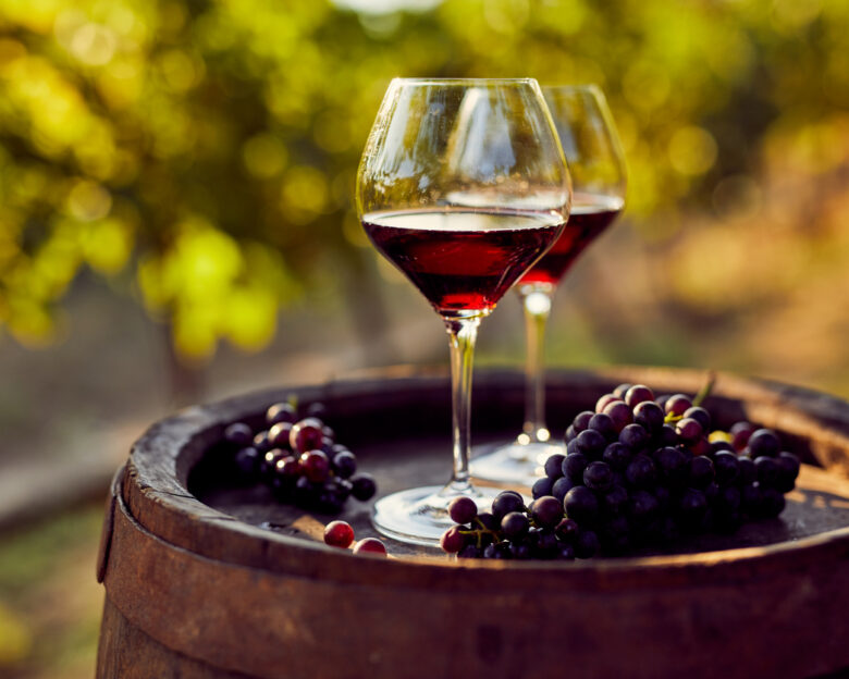 Two glasses of red wine on a wooden barrel in the vineyard