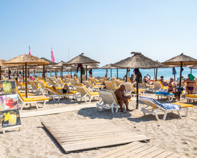 Kardamaina, Kos, Greece - People on sun loungers under umbrellas on the beach The town is a popular holiday destination.
