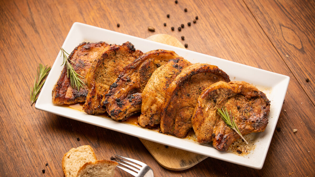 Grilled pork chop with spices and bred on wooden background