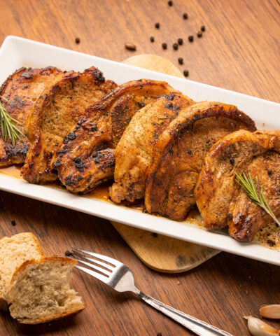 Grilled pork chop with spices and bred on wooden background