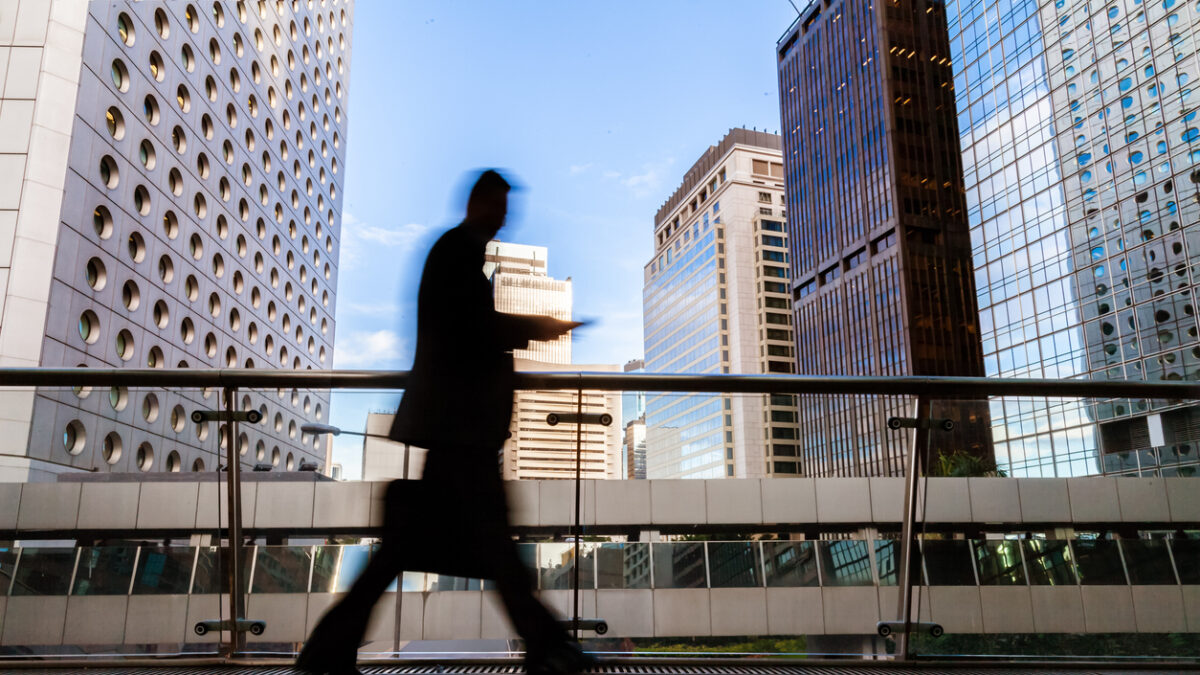 Blurred motion silhouette of businessman walking in Hong Kong’s Central District elevated walkway
