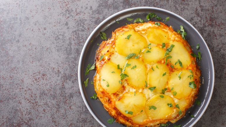 Pan haggerty is a simple one pot, stove top dish made with potatoes, onion and cheese closeup in the plate on the table. Horizontal top view from above