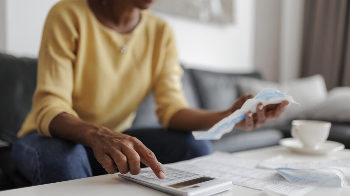 Close up of a mid adult woman checking her energy bills at home, sitting in her living room. She has a worried expression