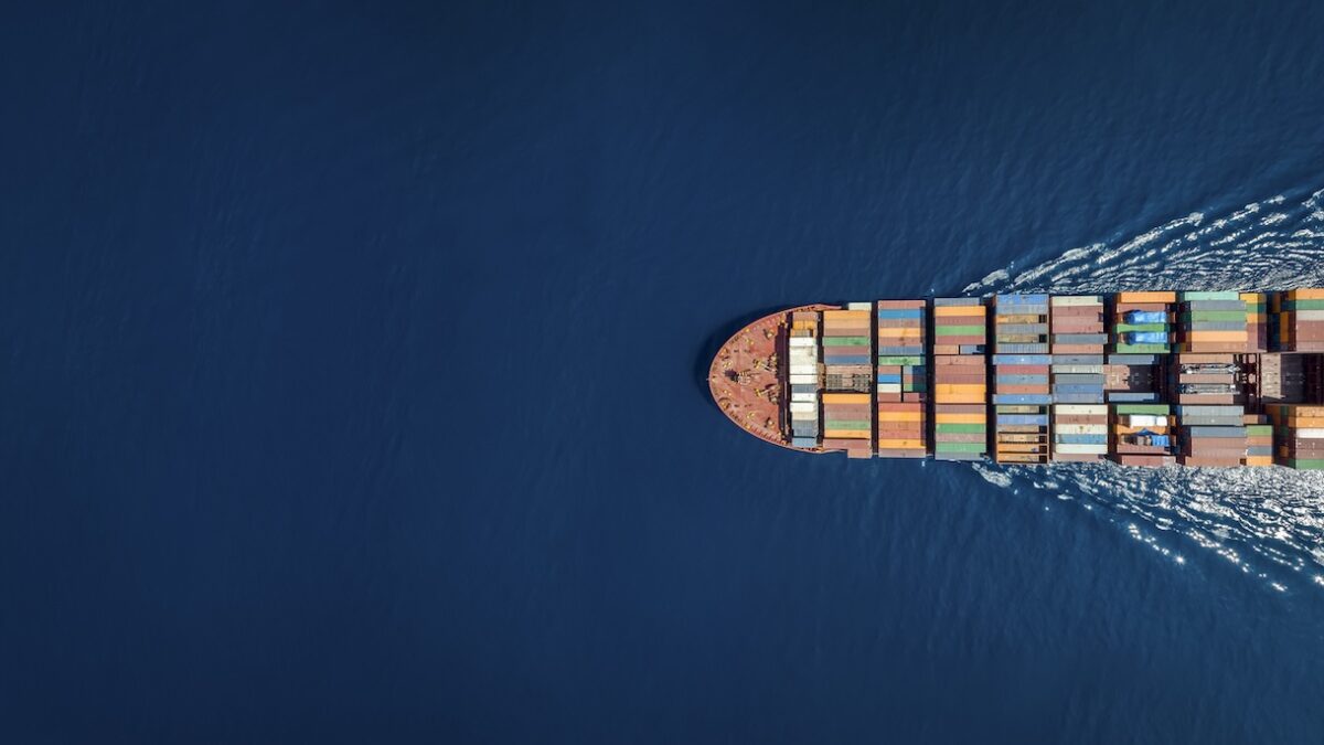 Aerial top down view of a large container cargo ship in motion over open ocean with copy space