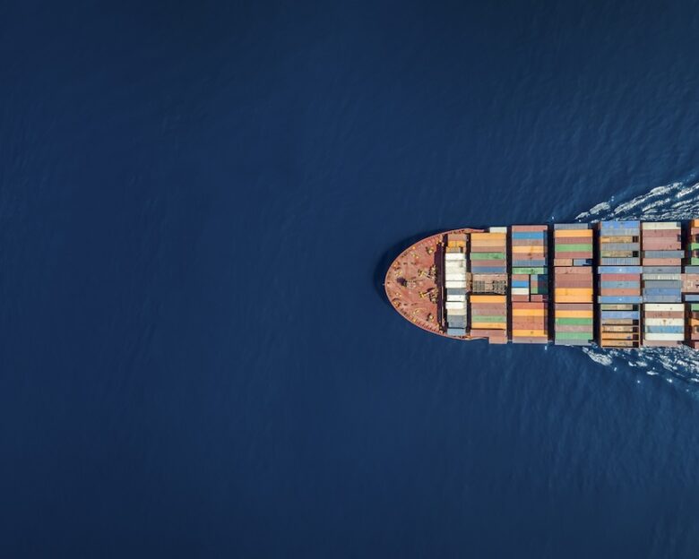 Aerial top down view of a large container cargo ship in motion over open ocean with copy space