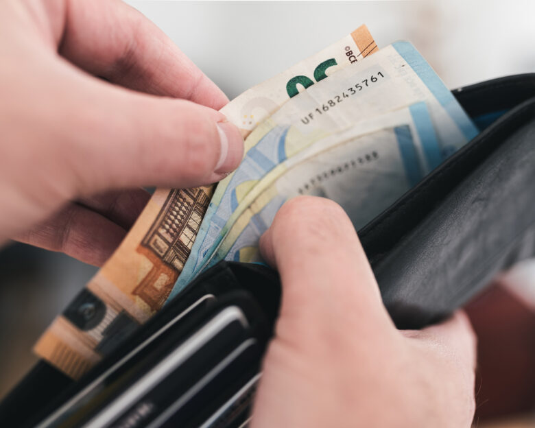 close-up view of hands taking money out of a wallet, spending cash concept