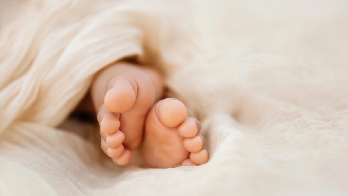 Newborn baby feet closeup on soft cream wrap in a selective focus - Image