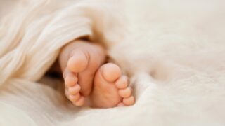 Newborn baby feet closeup on soft cream wrap in a selective focus - Image