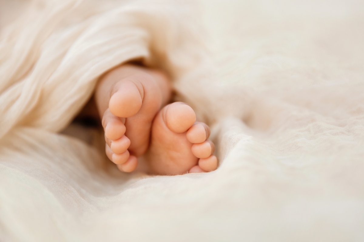 Newborn baby feet closeup on soft cream wrap in a selective focus - Image