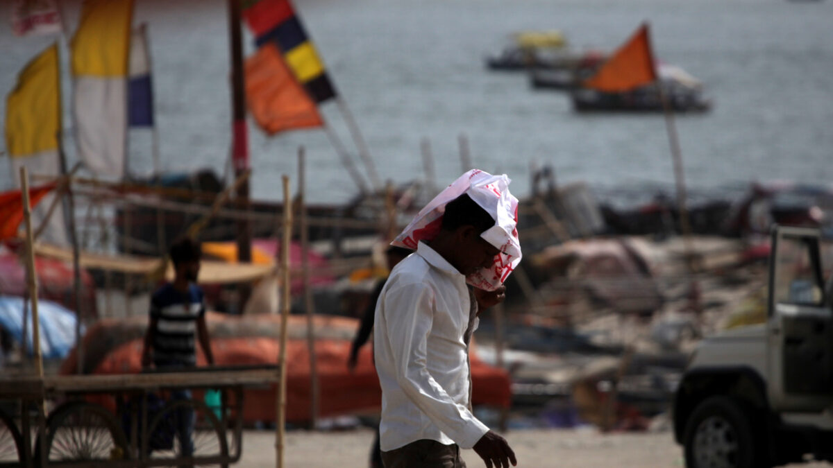 People walks during the heatwave conditions at the bank of river Gnages in Prayagraj, India