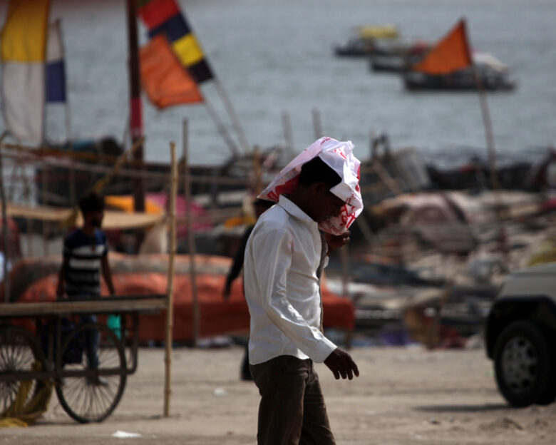 People walks during the heatwave conditions at the bank of river Gnages in Prayagraj, India