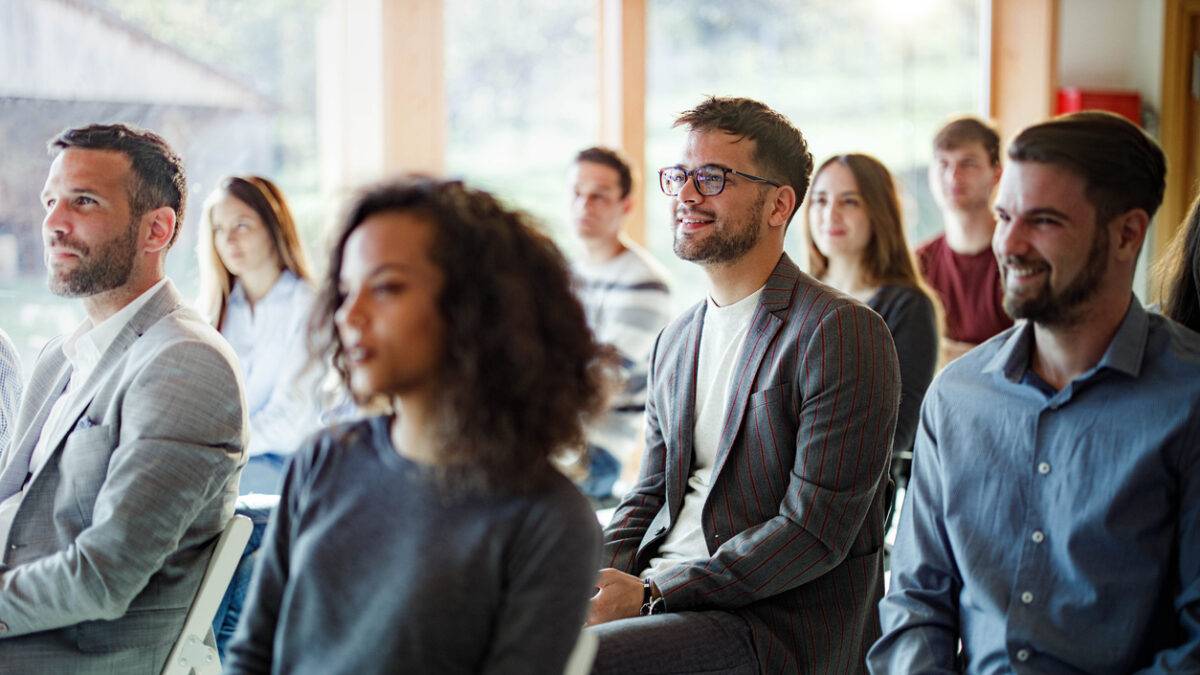 Large group of entrepreneurs attending an education event in board room. Focus is on happy man with eyeglasses