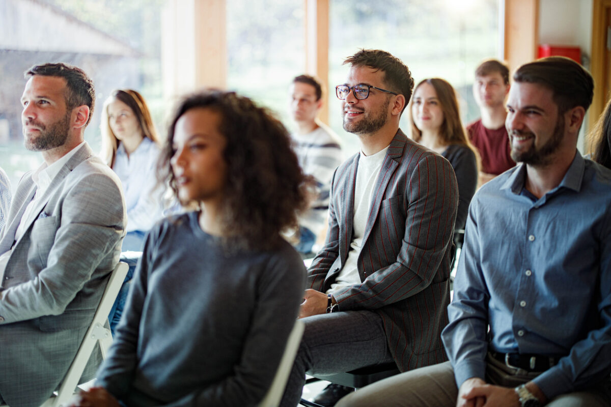 Large group of entrepreneurs attending an education event in board room. Focus is on happy man with eyeglasses